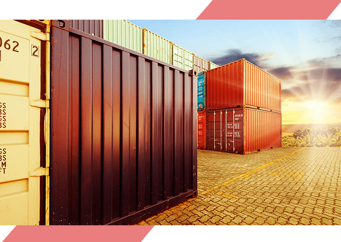 A red container is next to a brown fence.